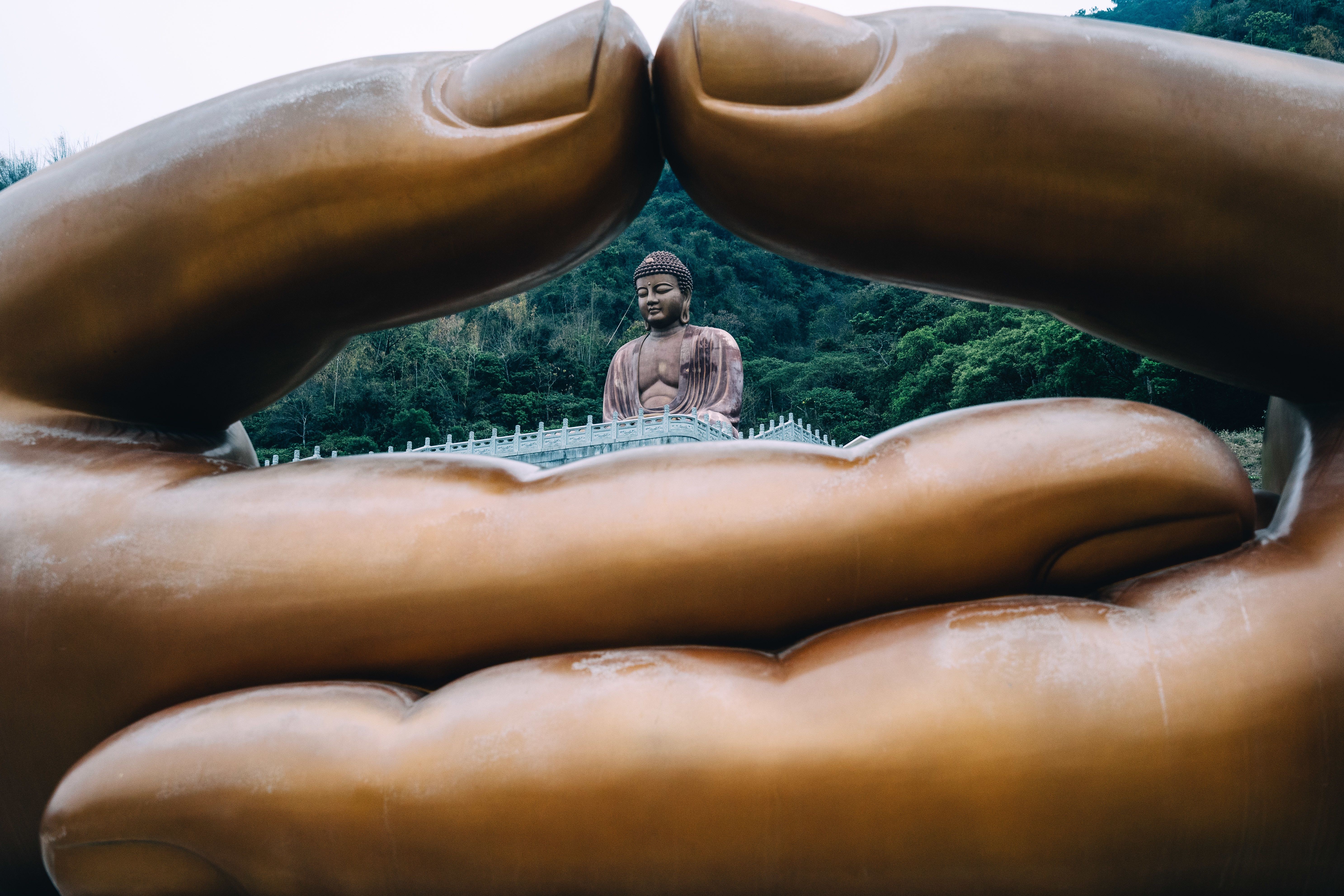 A statue of Buddha though the hands of another statue